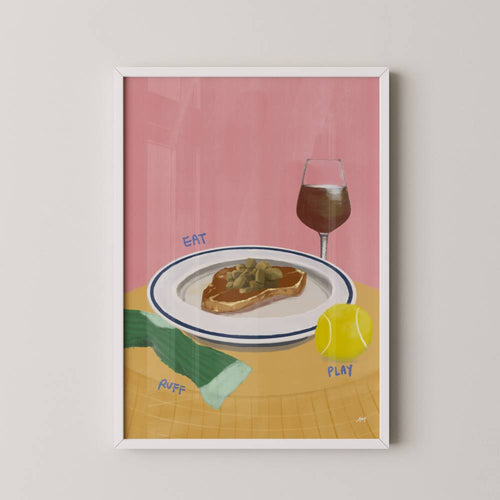 Framed artwork with a pink background, plate of food, glass of wine, tennis ball, and text on a white wall.