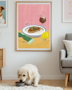 Dog eating from a bowl on a rug with a framed art print of food and wine, tennis ball and sock in the background
